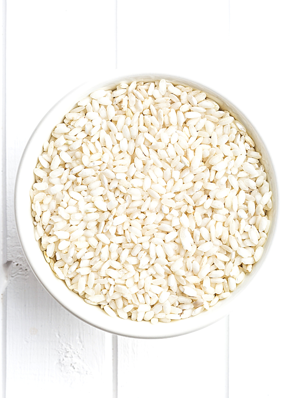 Arborio Rice in a white bowl on a white background.