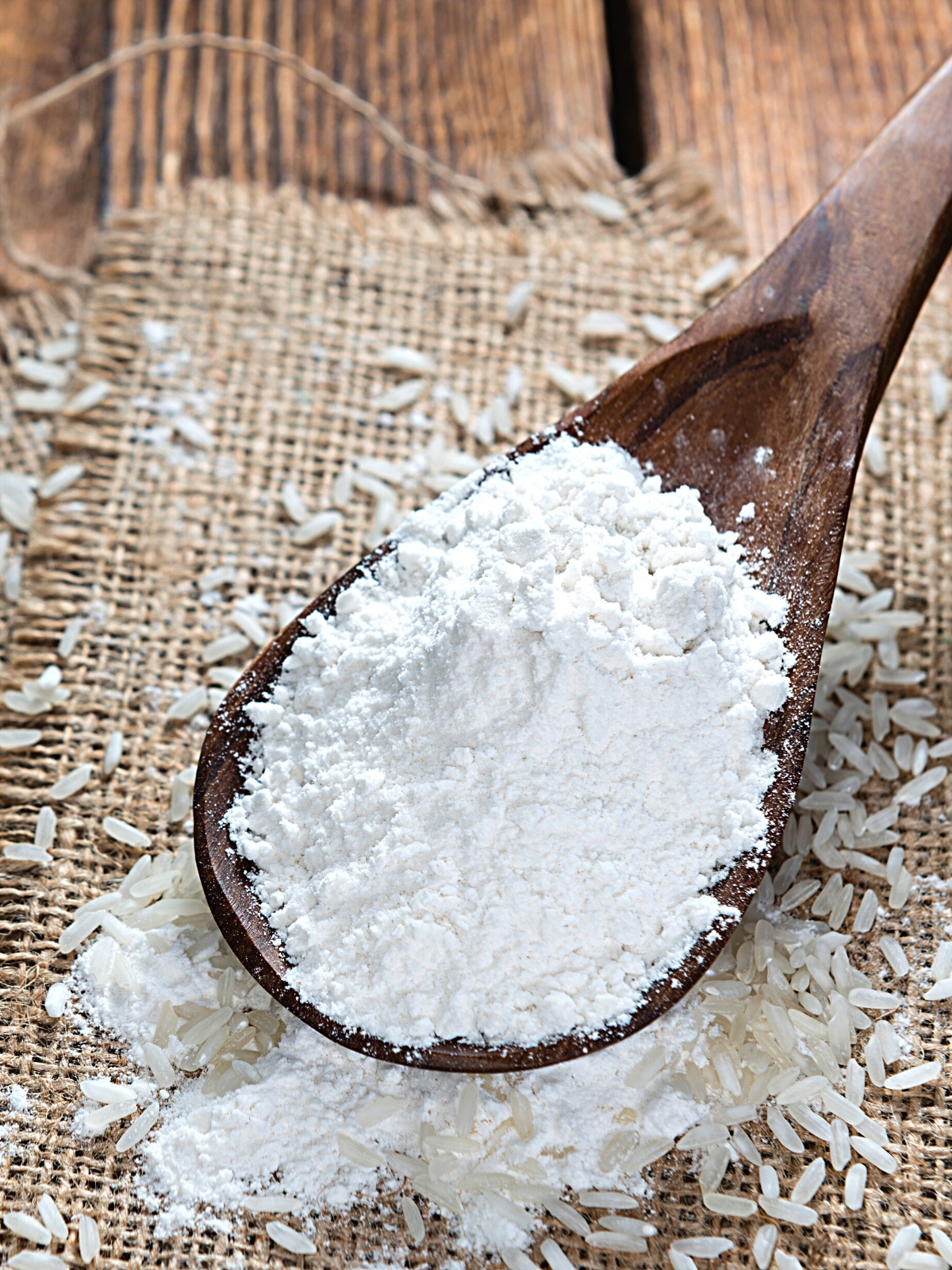 Rice Flour on a wooden ladle, with a few raw rice scattered underneath the ladle.