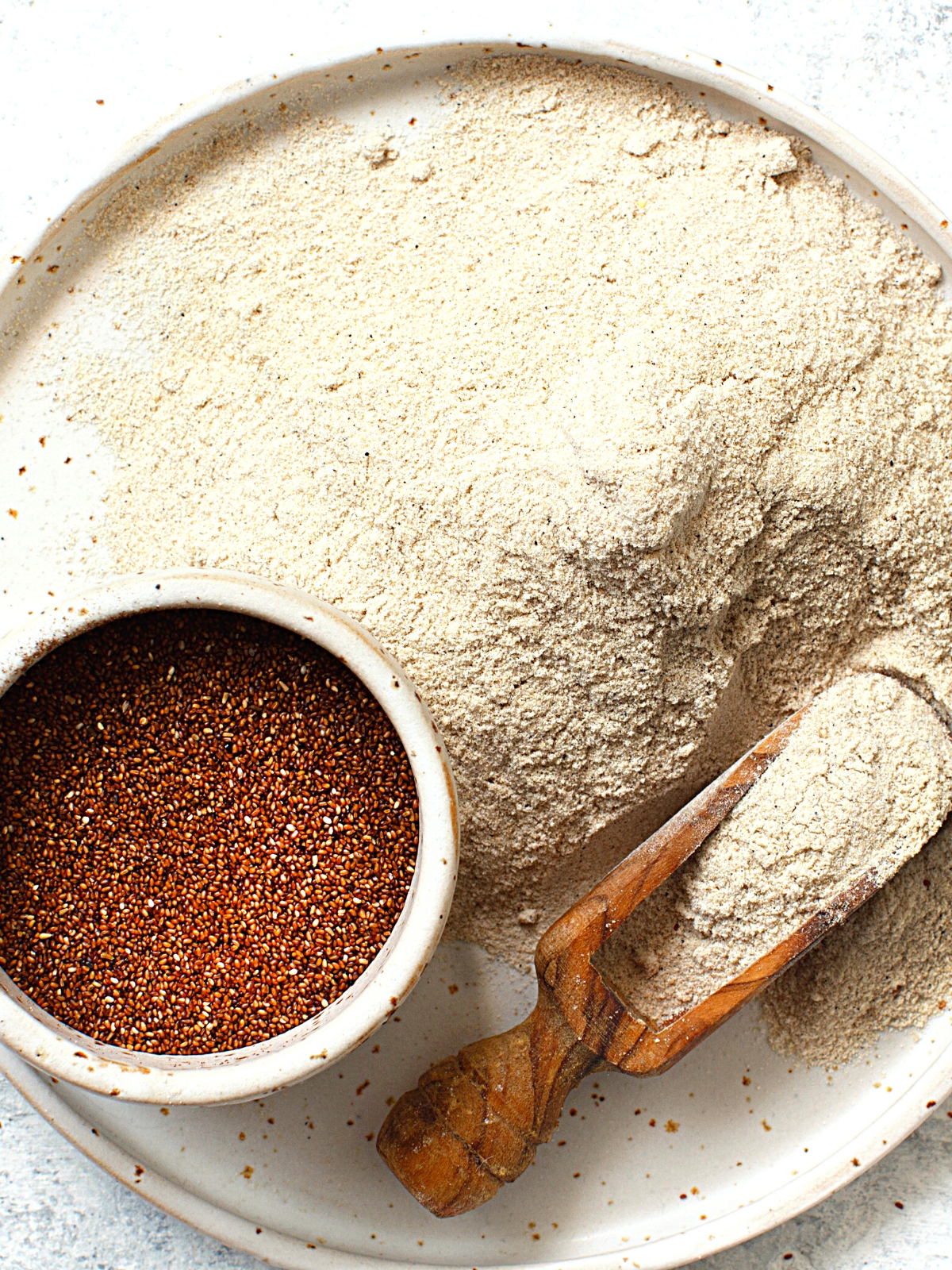 Teff seeds and Teff flour on a white plate.