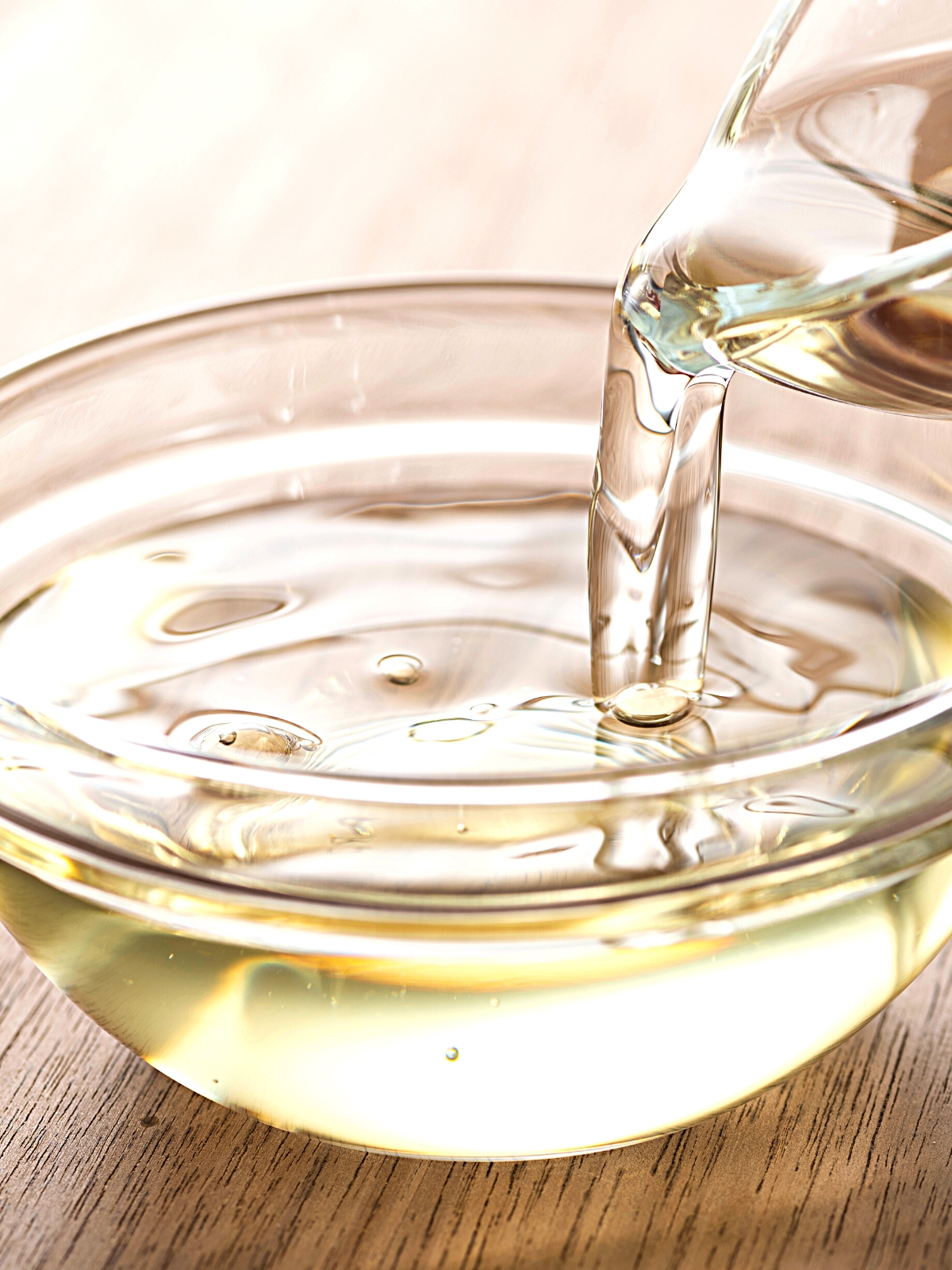 Pouring of Mirin japanese cooking wine (sake) in a glass bowl.