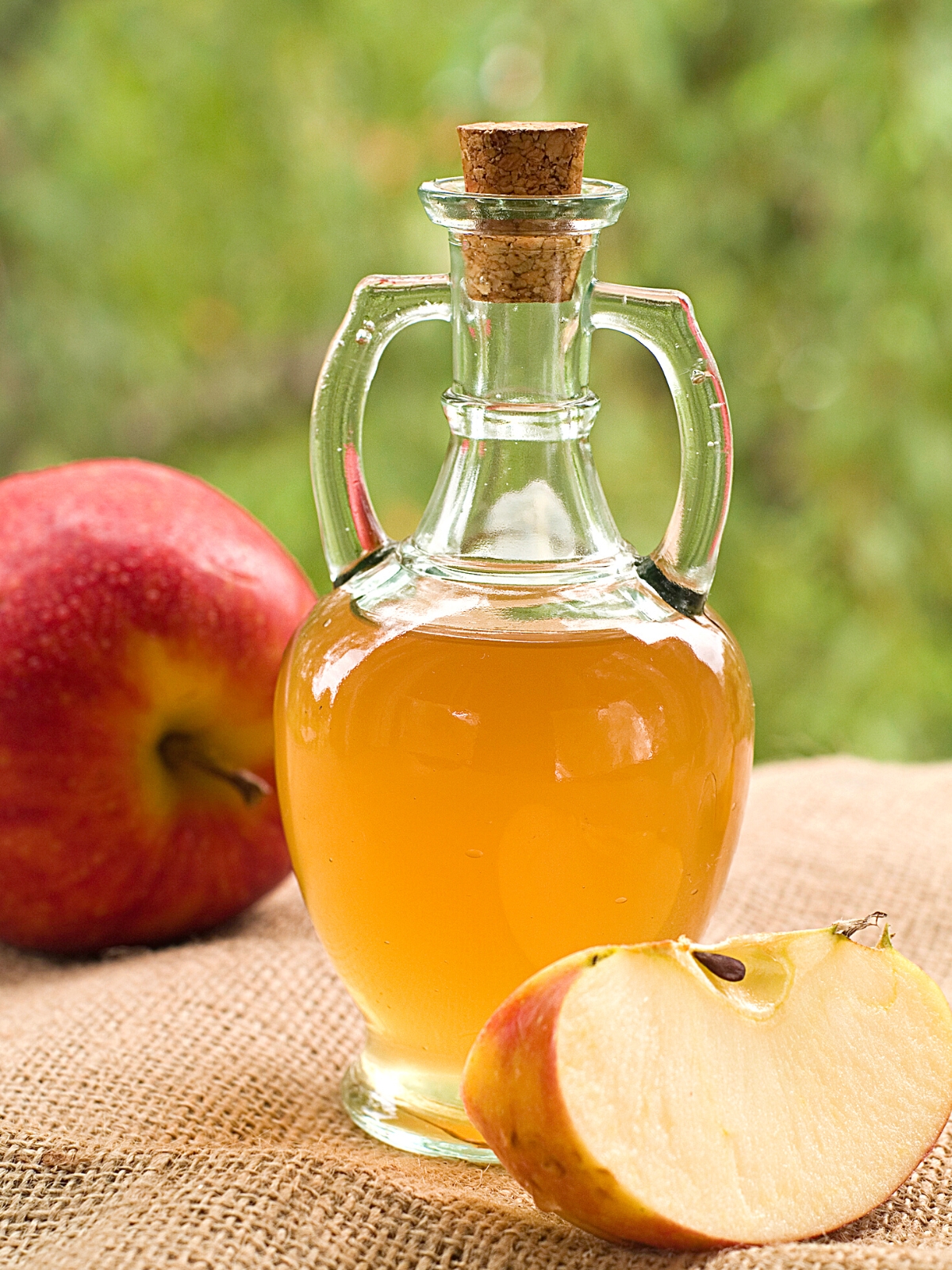 apple cider vinegar in a glass jar on top of a sack cloth.