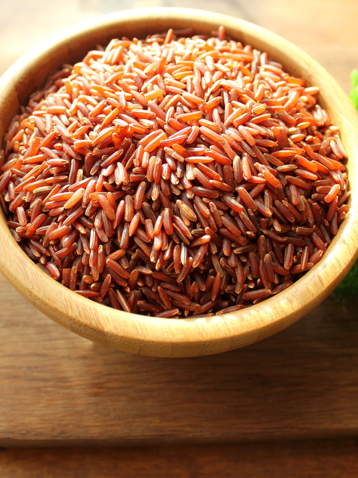 A wooden bowl with red rice in it.