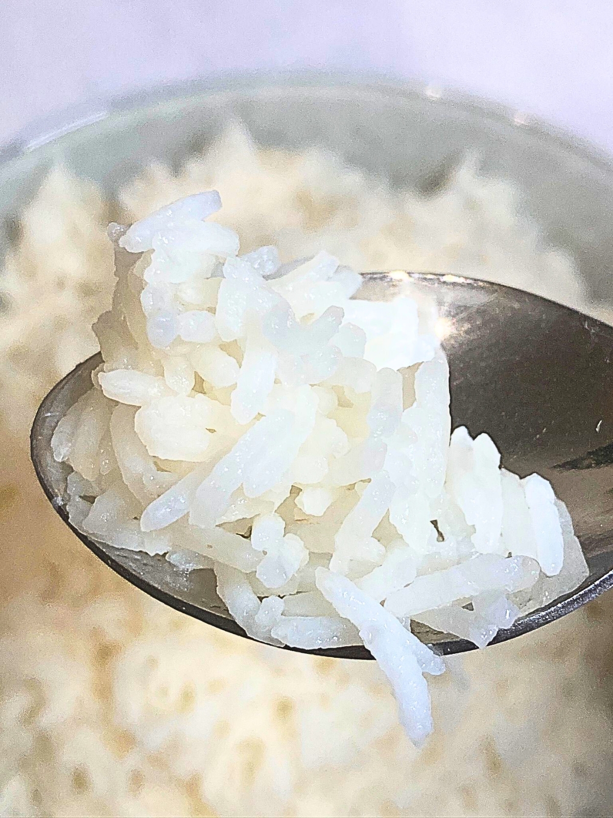 Spoon with cooked basmati rice lifting from bowl.