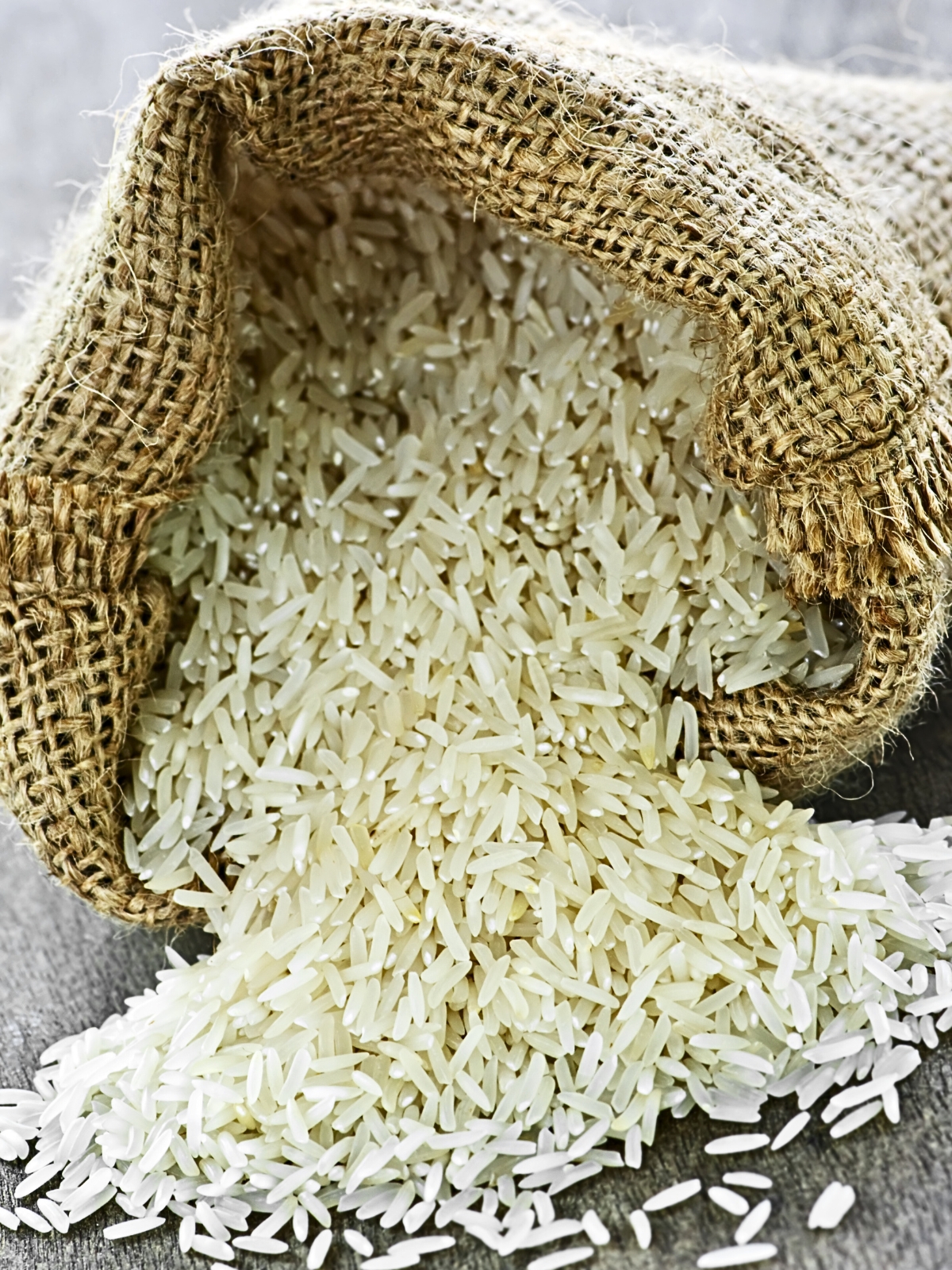 Long Grain Rice in Burlap Sack placed on a grey surface.