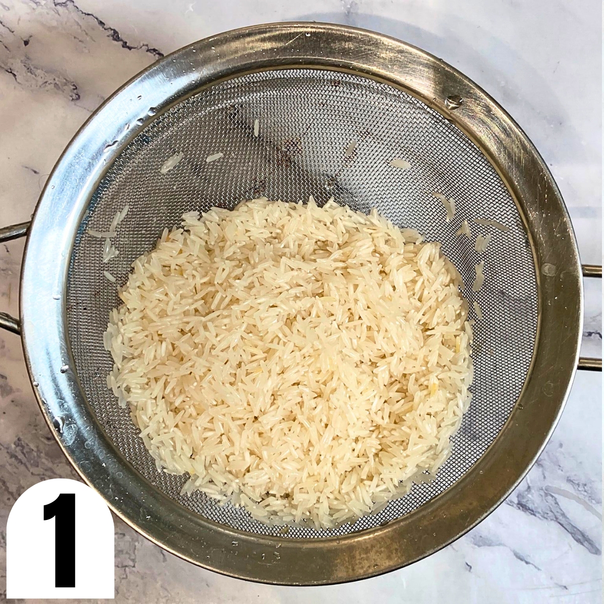 Rinsed white basmati rice in a metal sieve.