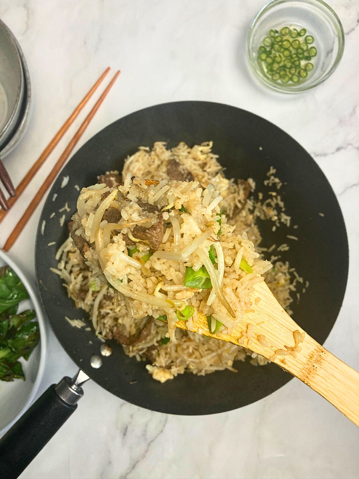 Steak fried rice in a wooden spoon lifting from a wok.