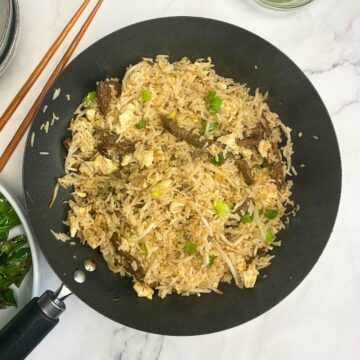 Fried rice with steak and green onion in wok.