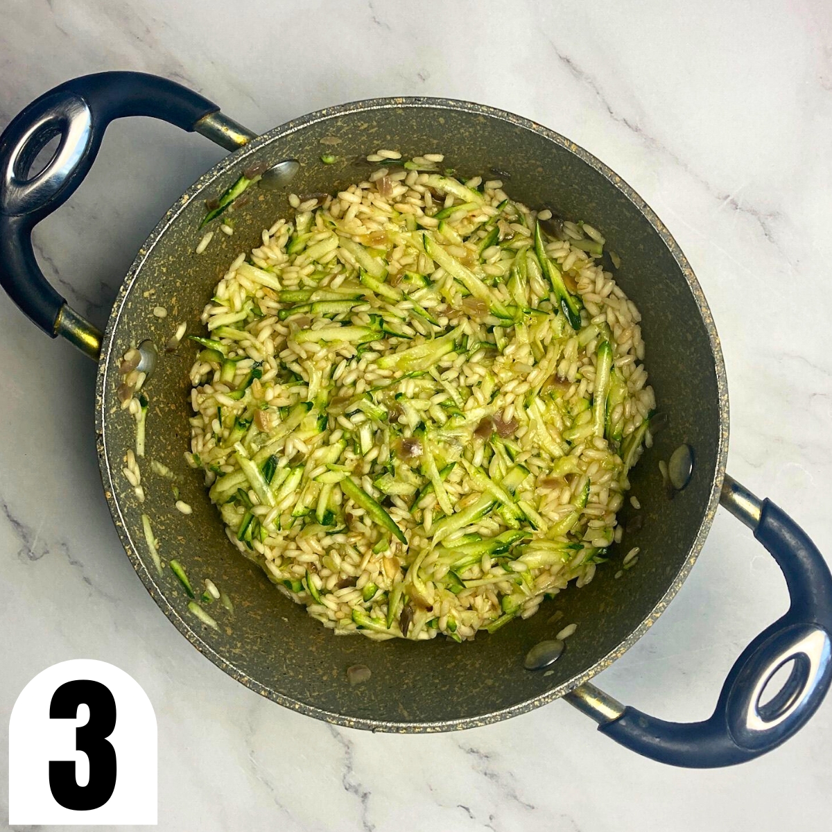 Grated zucchini and risotto rice in saucepan.