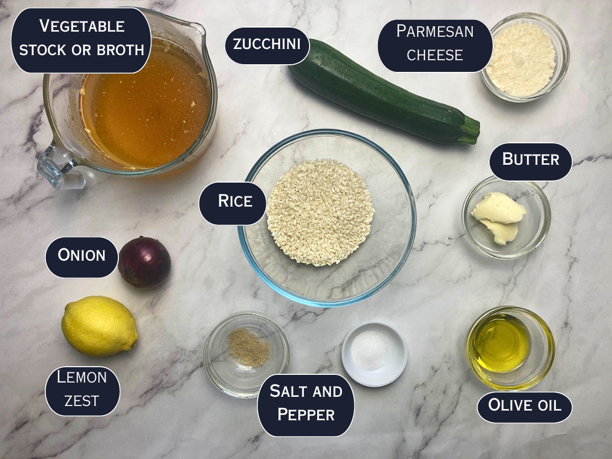 Ingredients needed to make lemon zest and zucchini risotto displayed on a marble countertop.