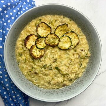 Lemon zucchini risotto with fried zucchini roundels in a grey bowl.