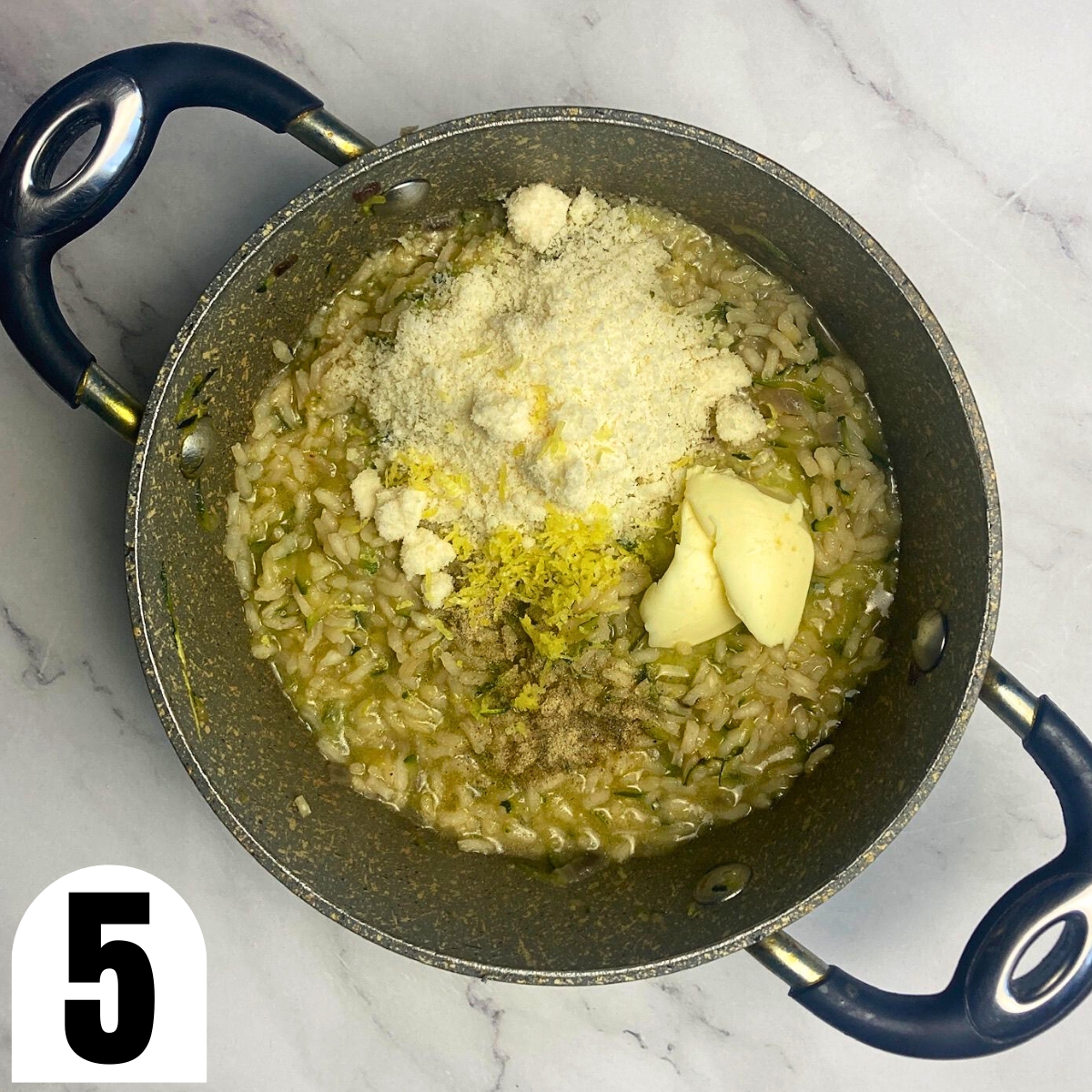 Zucchini risotto with lemon zest, Parmesan, butter, and white pepper in a saucepan.