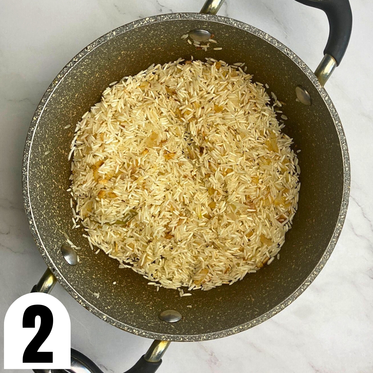 Basmati rice toasted with oil and onion in grey saucepan.