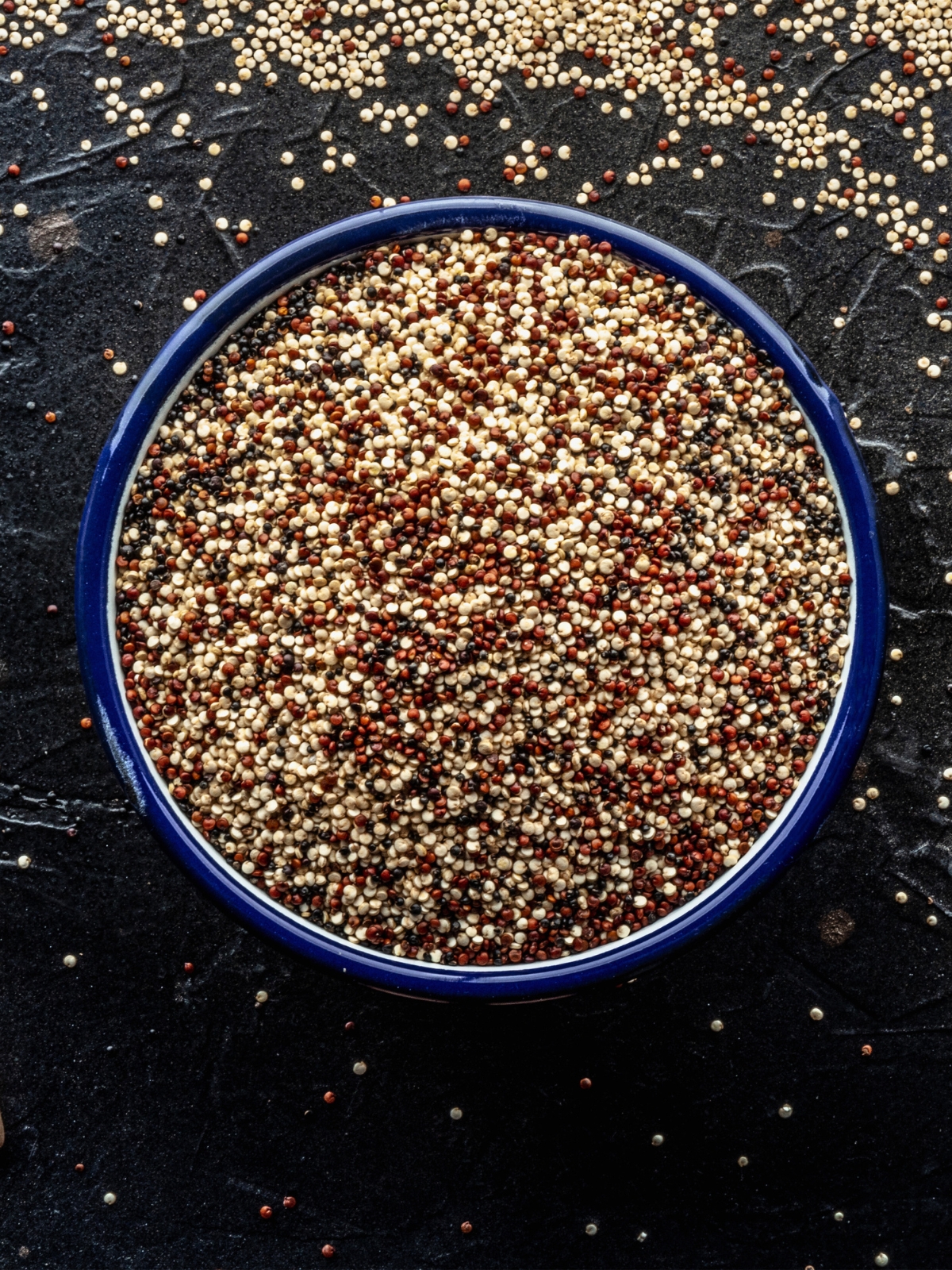 Mixed white, red and black quinoa seeds in a bowl.