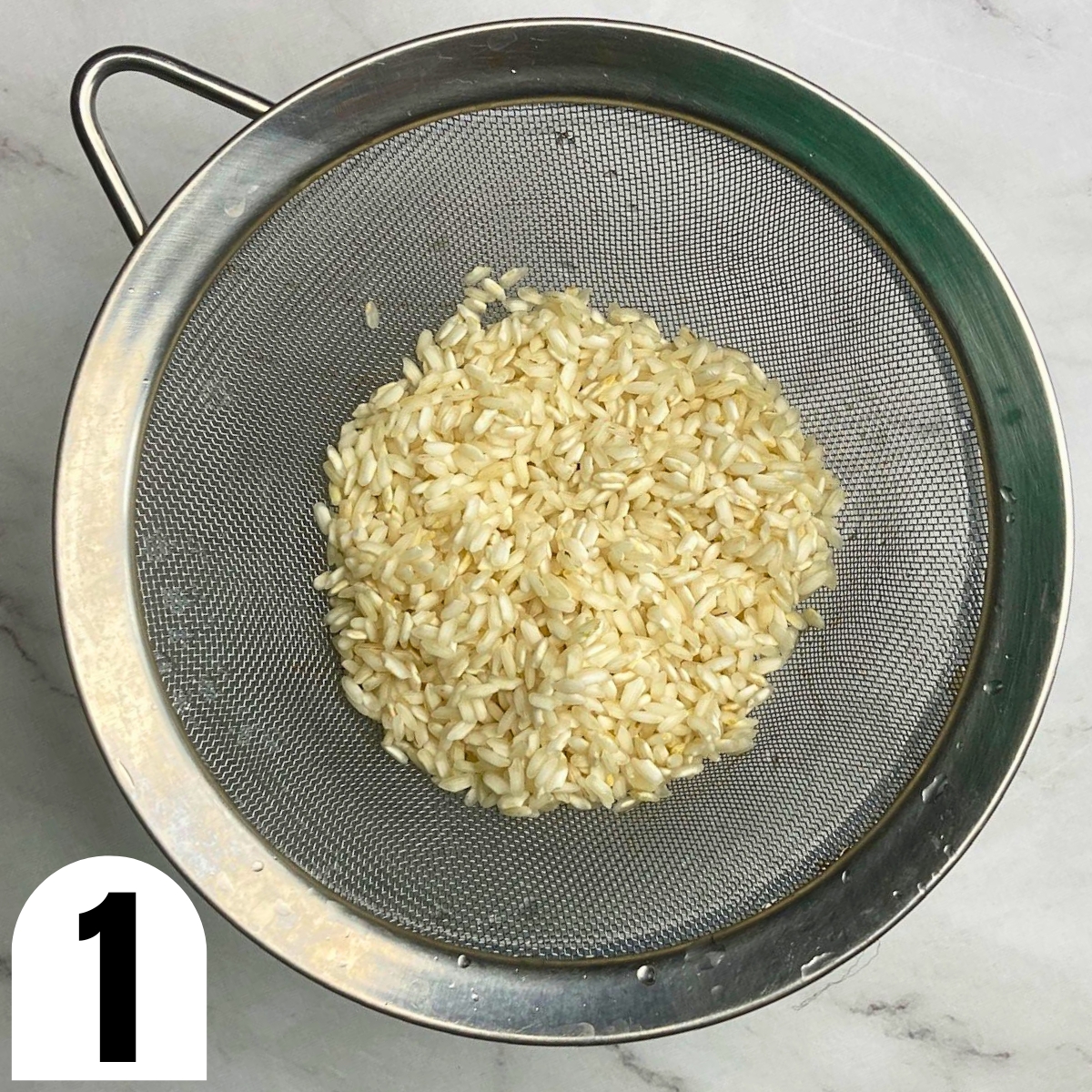 Rinsed Carnaroli rice in a metal sieve.
