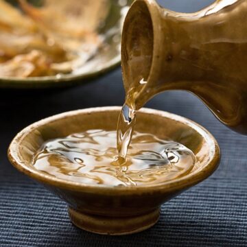 Sake being poured into a ceramic bowl.