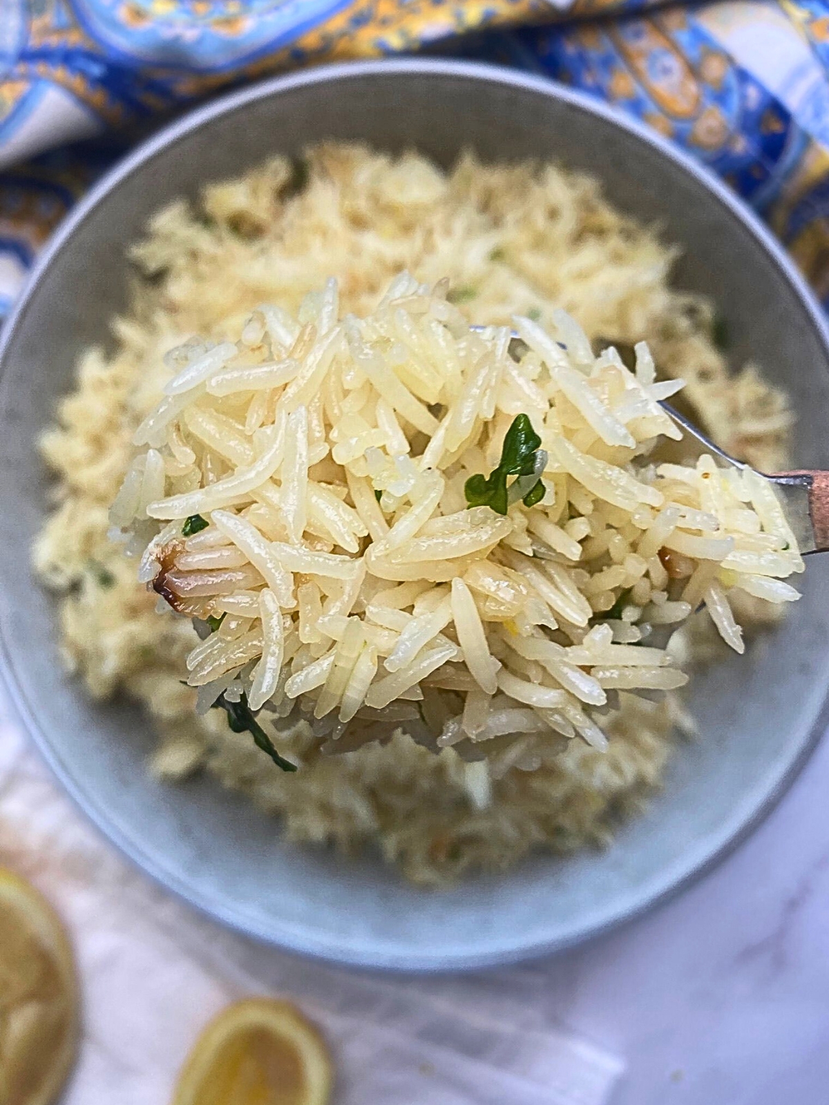 Spoon of lemon rice pilaf lifting from a bowl.