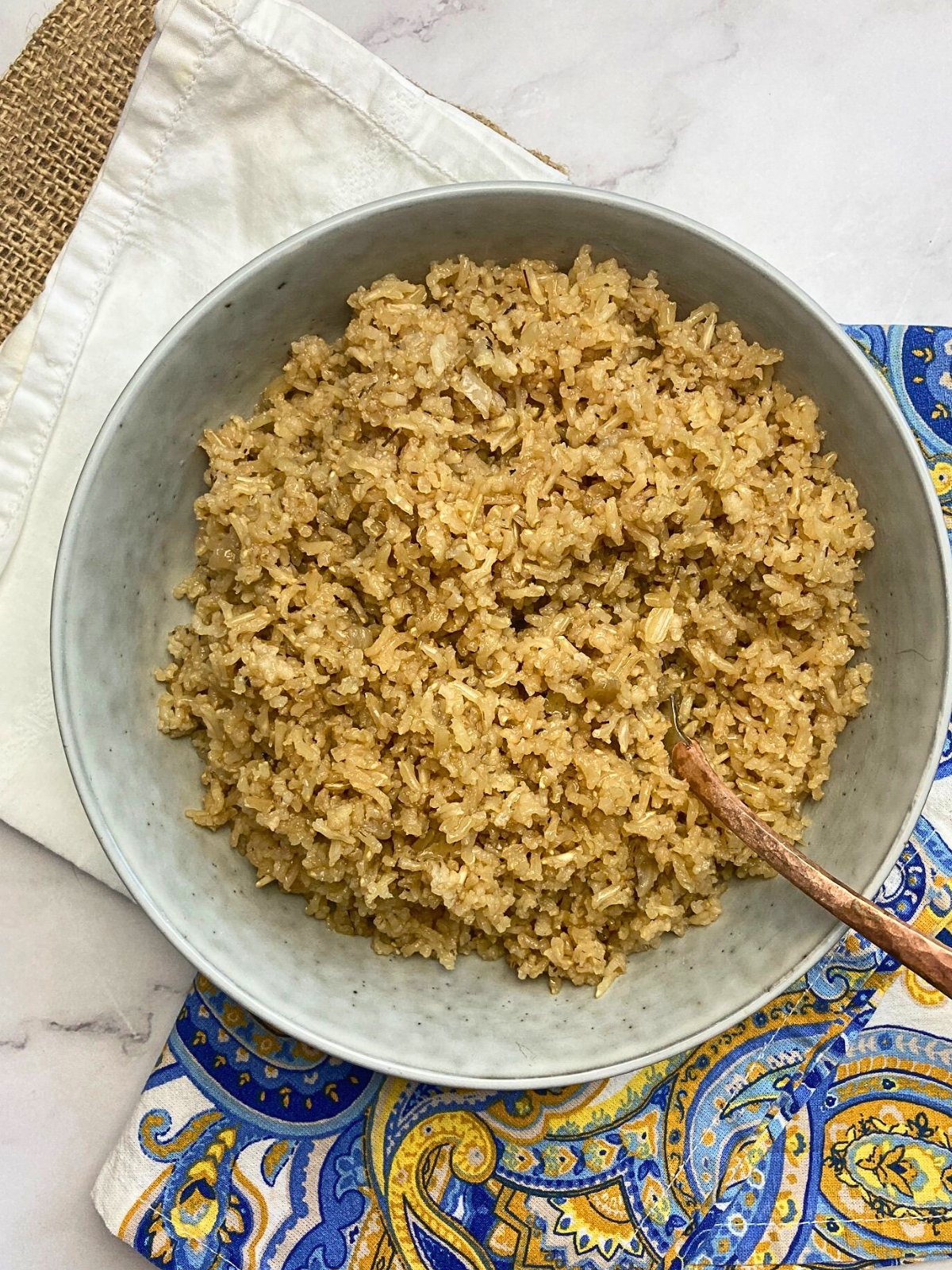 Bowl filled with brown rice pilaf with a spoon in it.