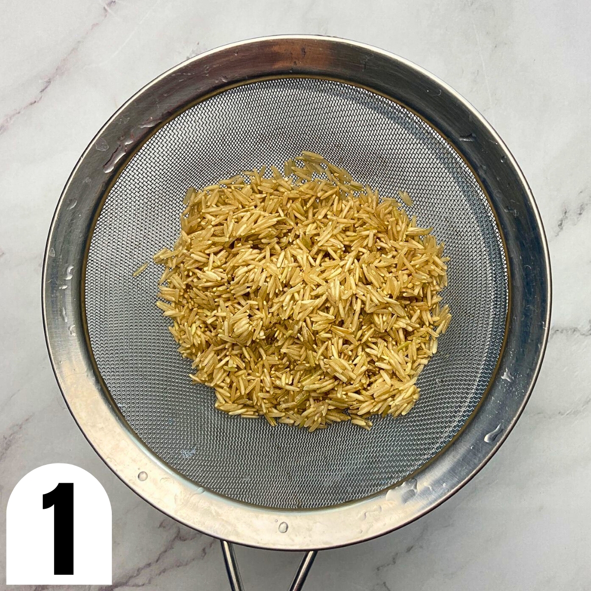 Rinsed rice in a metal sieve.