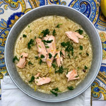 Sicilian salmon risotto in a grey bowl with fresh parsley sprinkled on top.
