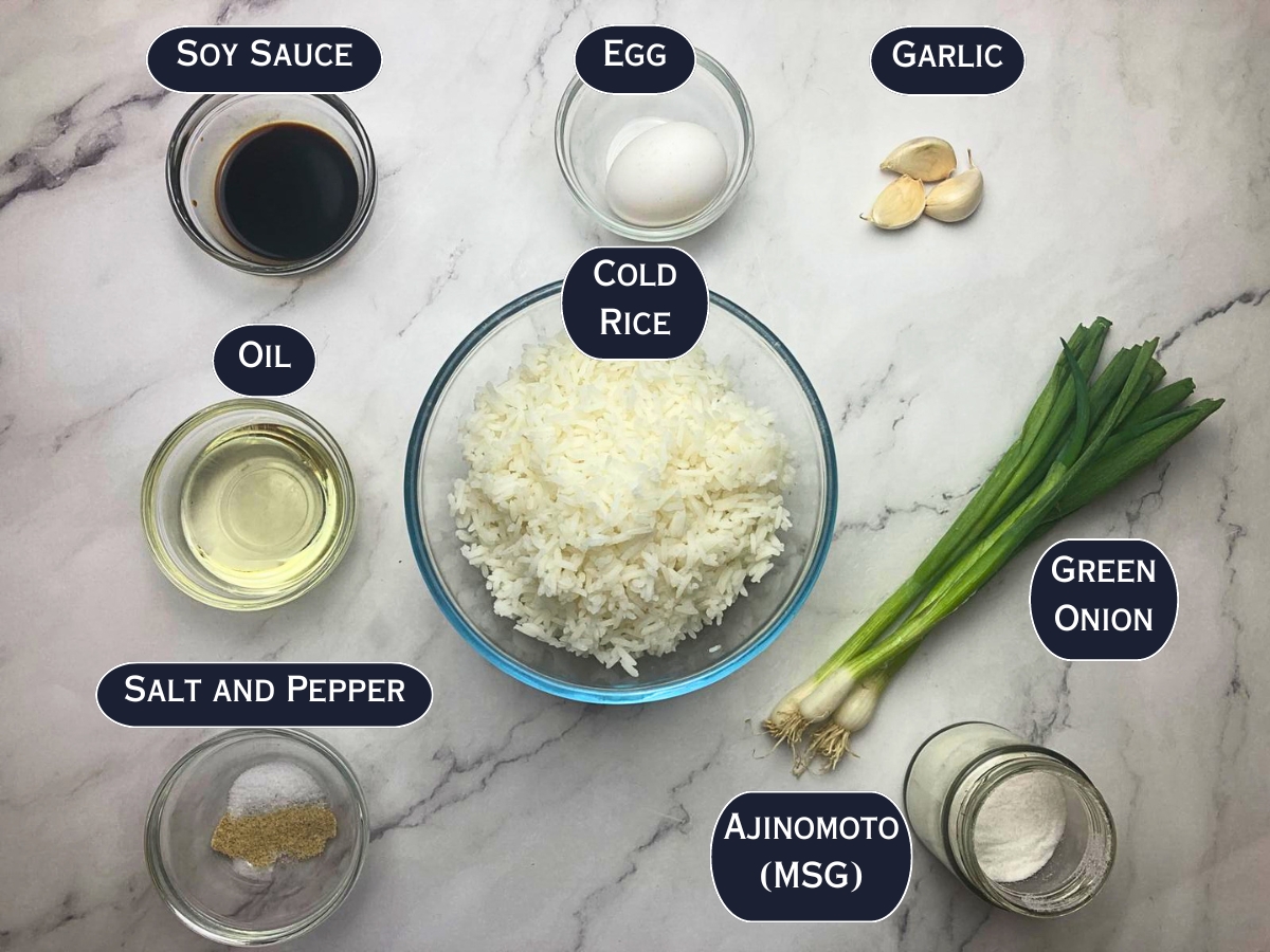 Ingredients needed to prepare garlic fried rice displayed on a marble countertop.