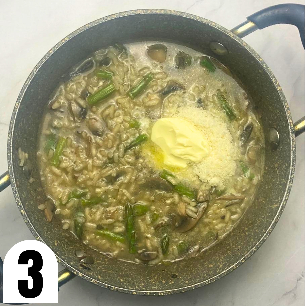 Grey saucepan with risotto with asparagus and mushrooms with butter and grated Parmesan on top.