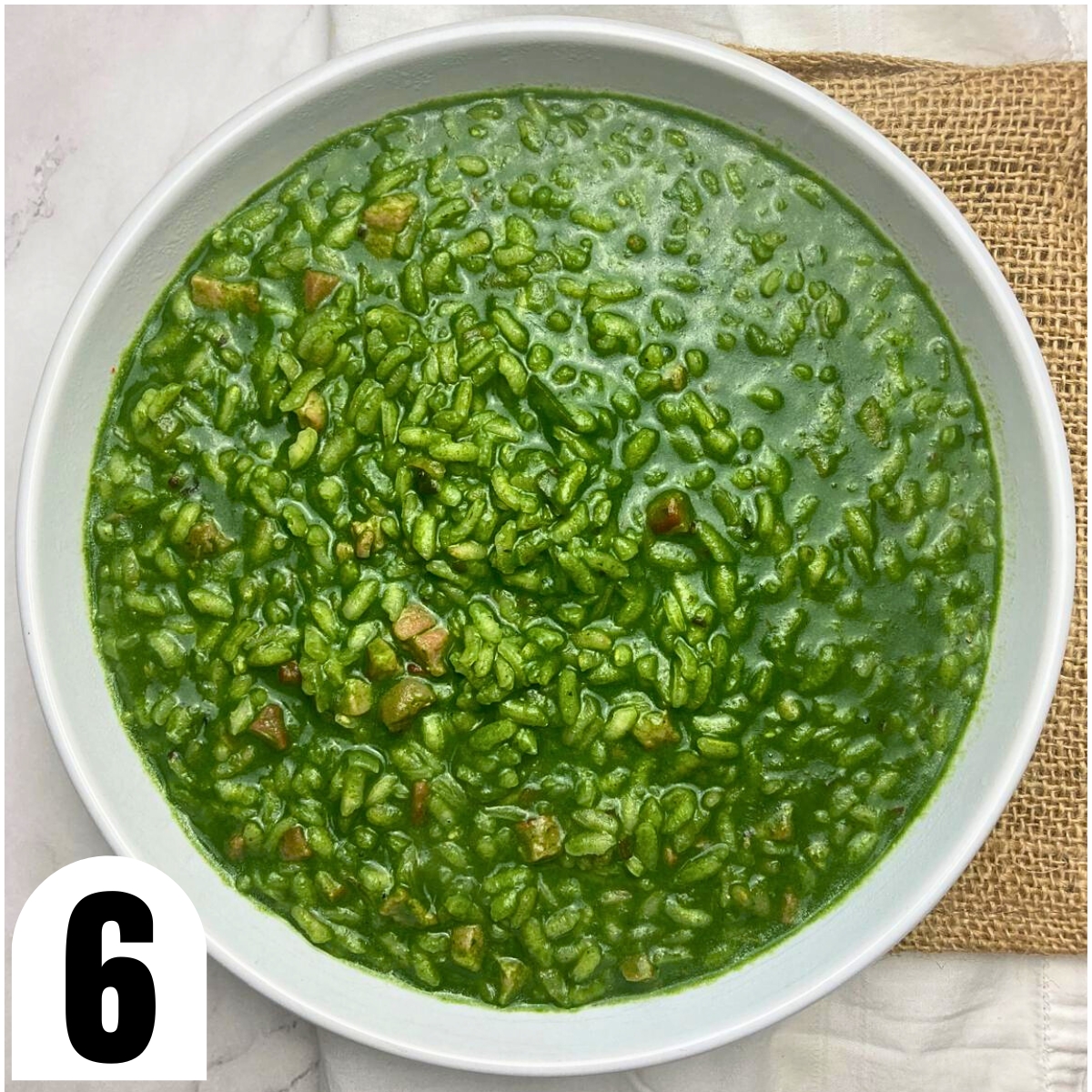 White bowl filled with spinach risotto with cubes of pancetta.