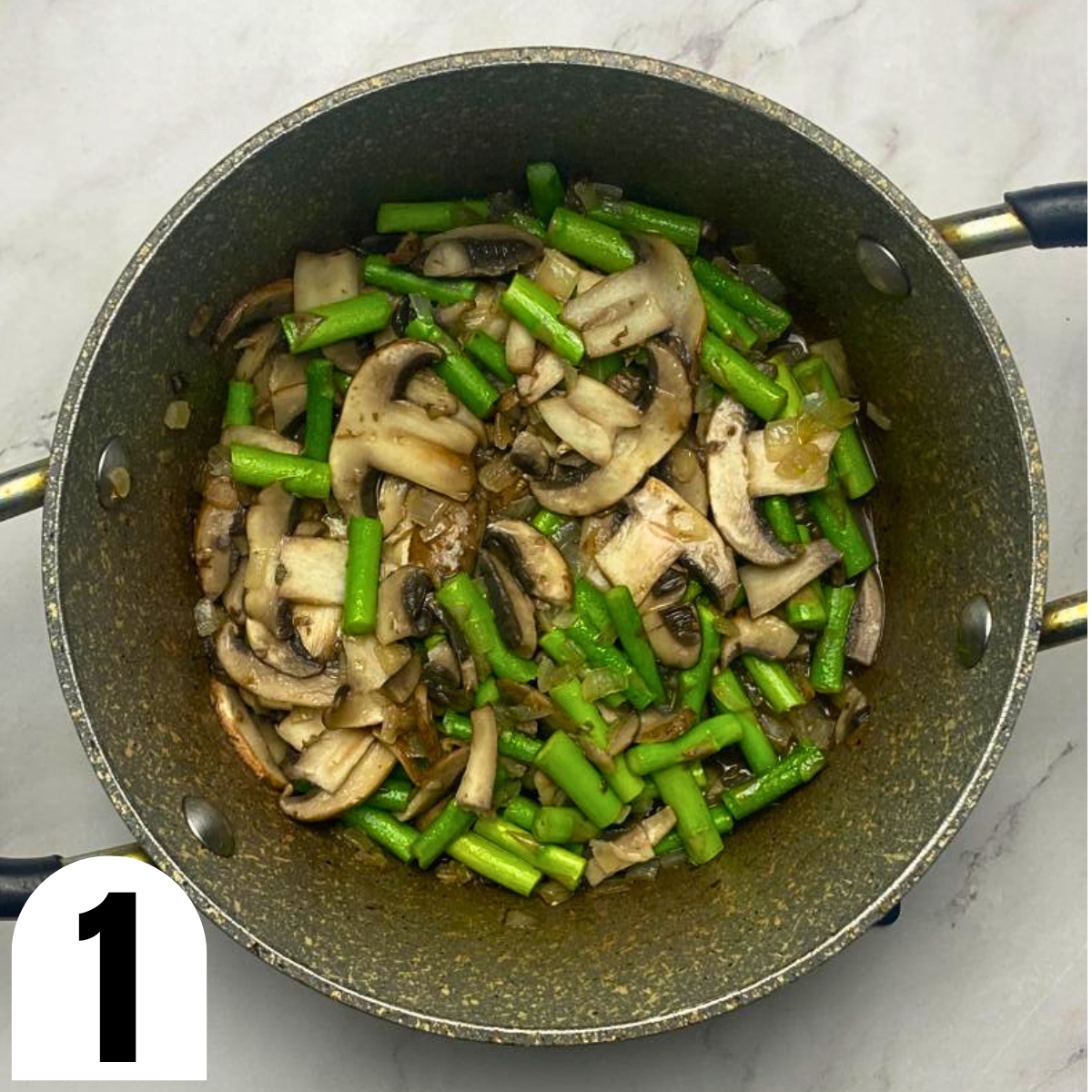 Grey saucepan with sauteed sliced mushrooms and chopped asparagus.