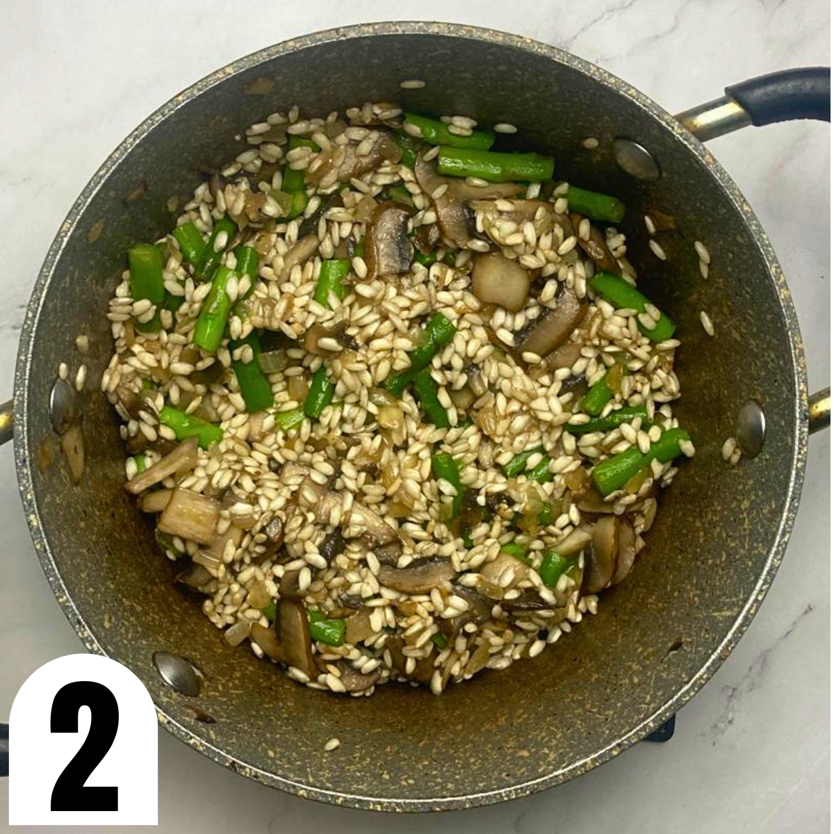 Grey saucepan with risotto rice, mushrooms, and asparagus.