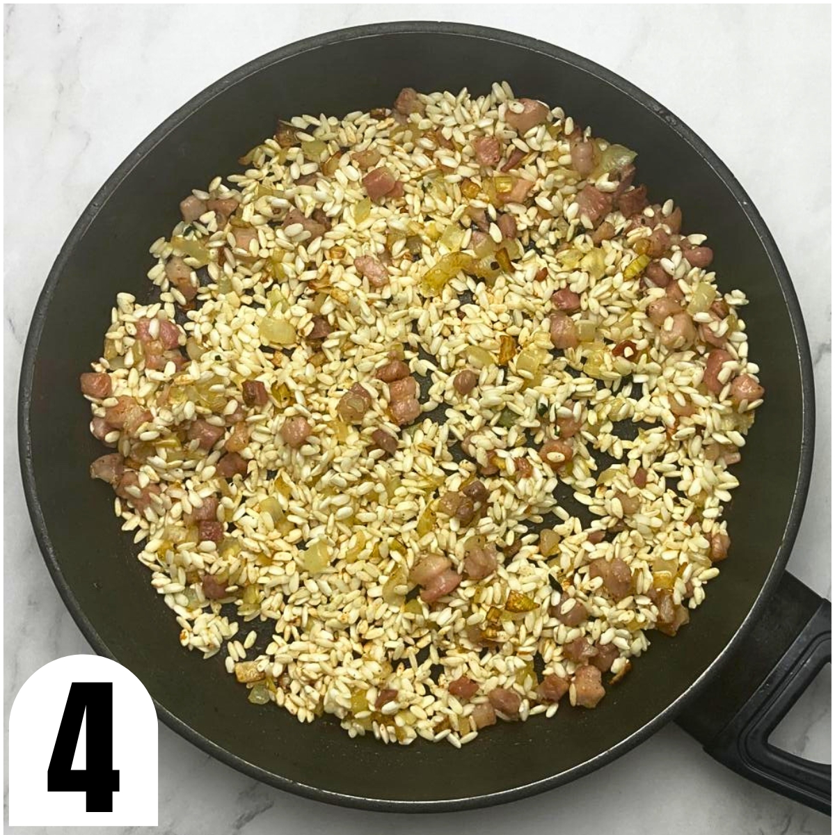 Frying pan with sauteed onion and pancetta and toasted risotto rice.